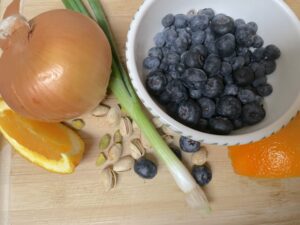 Flavonoid-rich whole foods from kitchen which includes blueberries, citrus, onions, green onions with tops and pistachios used to build nutrient variety with Tip-Top Food app